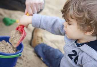 Dreng skovler sand op i en spand